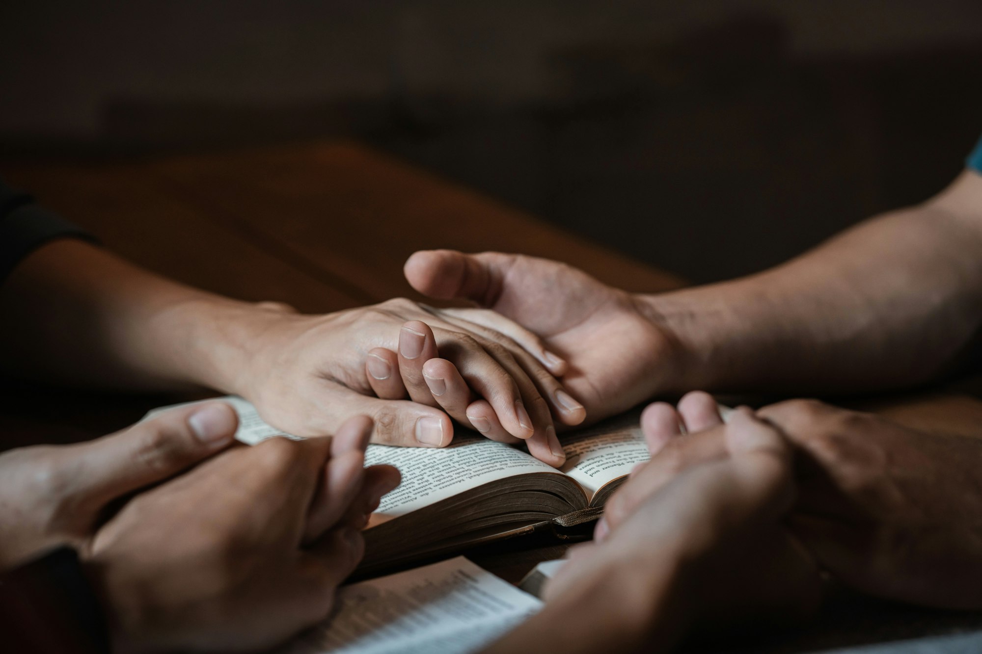 A group of young Christians holding hands in prayer for faith