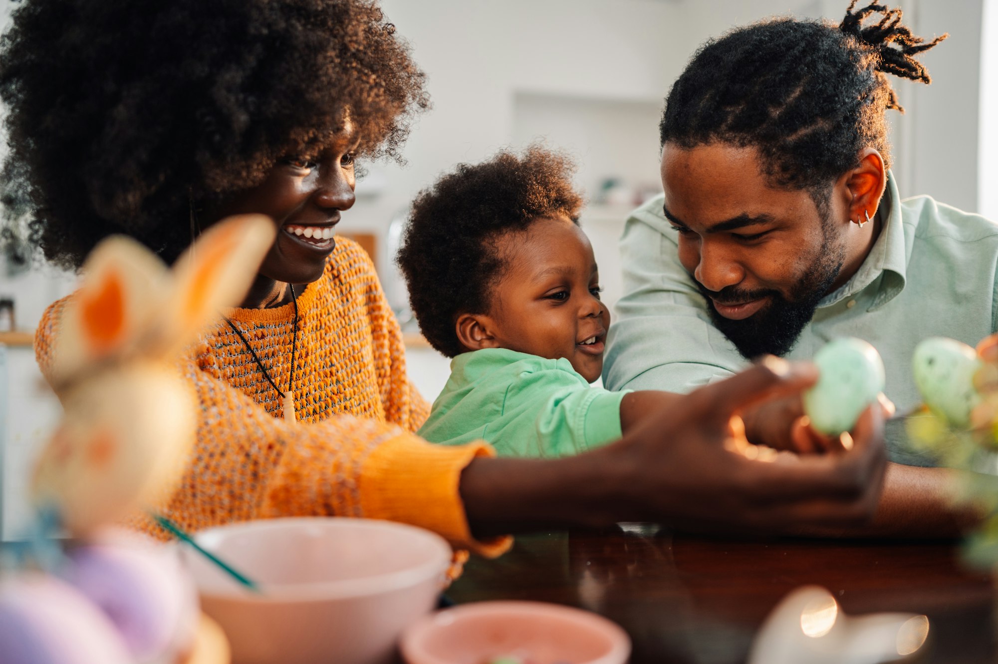 African american parents with toddler son painting colorful eggs together