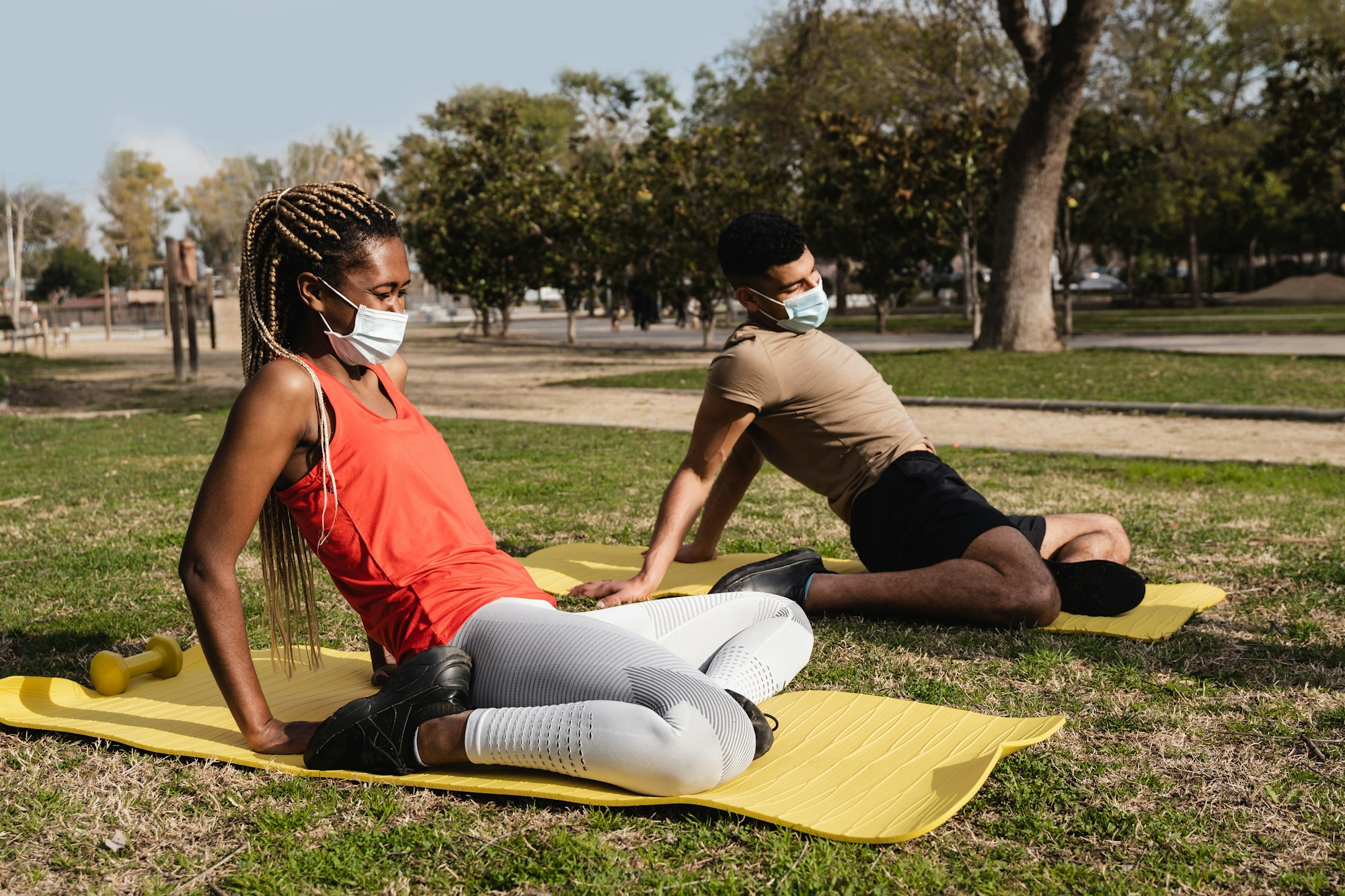 Black people doing yoga routine outdoor while wearing safety masks outdoor at city park