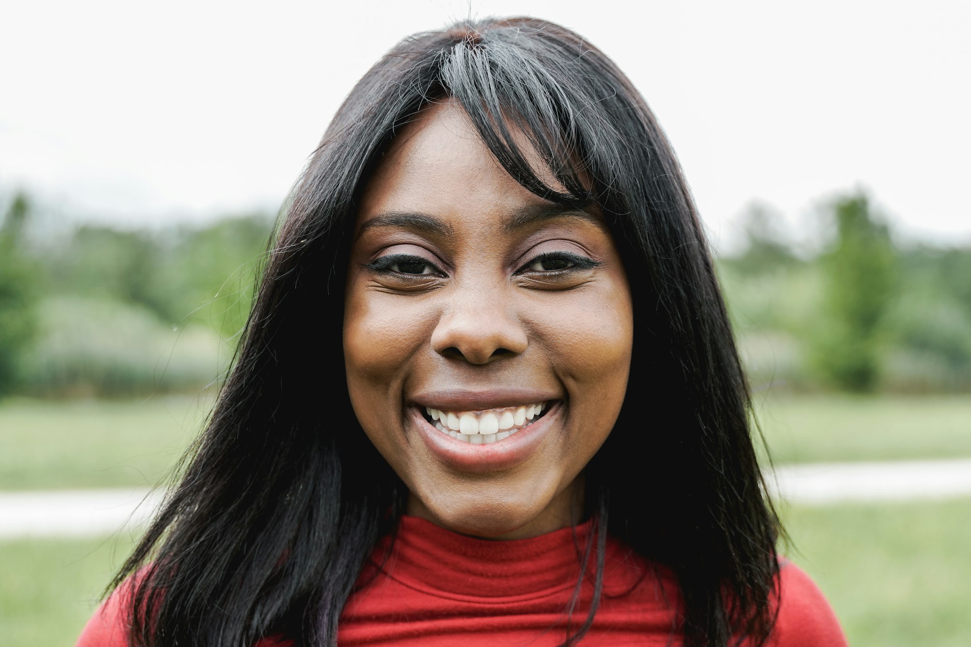 Happy African American young woman smiling on camera outdoor - Focus on face