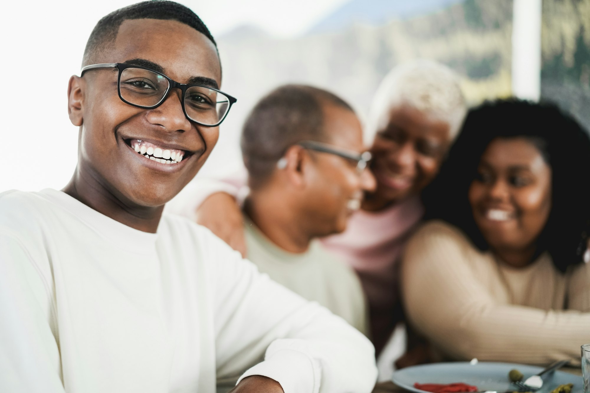 Happy black young man eating lunch with his family