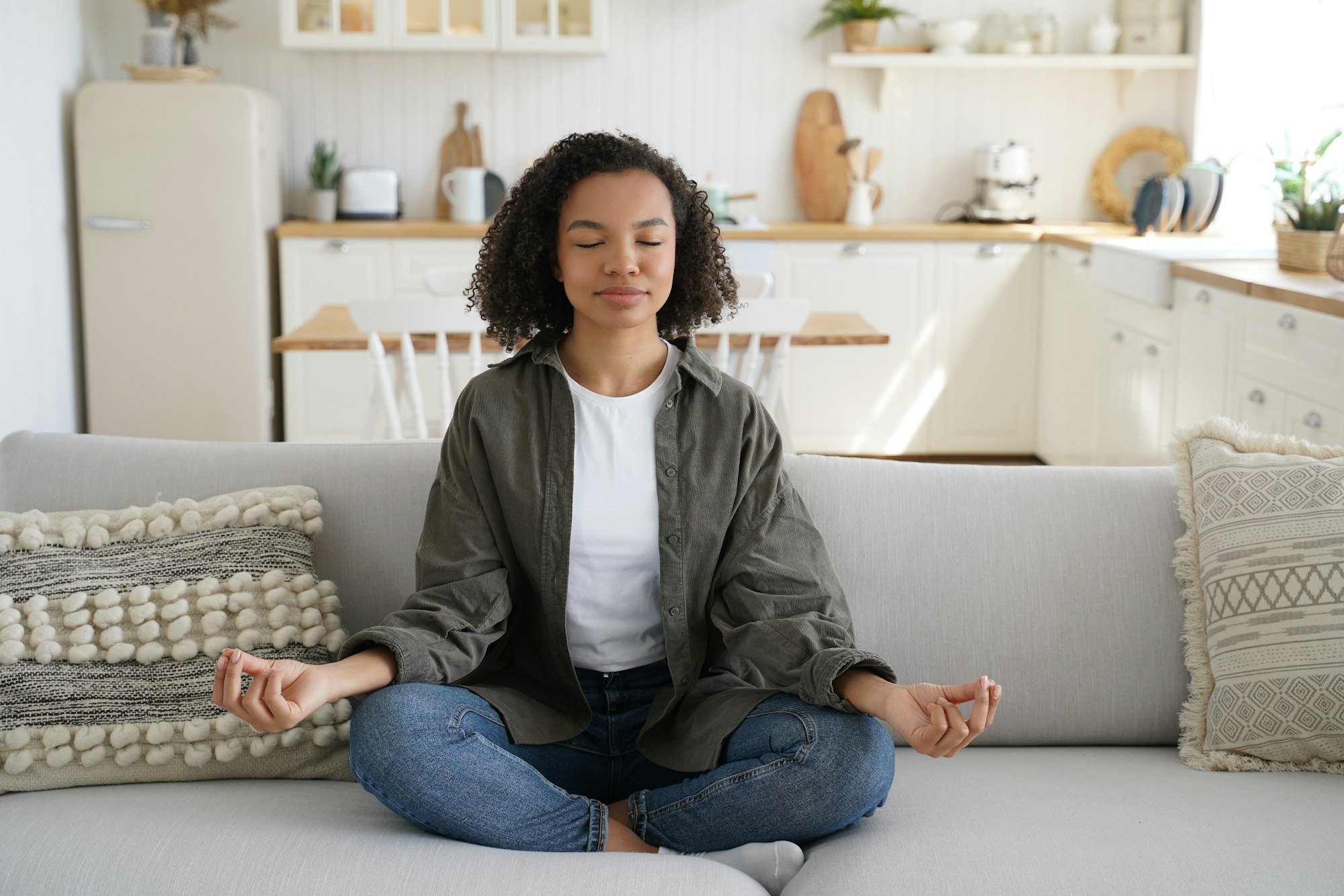 Teenage afro girl is practicing yoga at cosy home. Wellness and emotional wellbeing, stress relief.