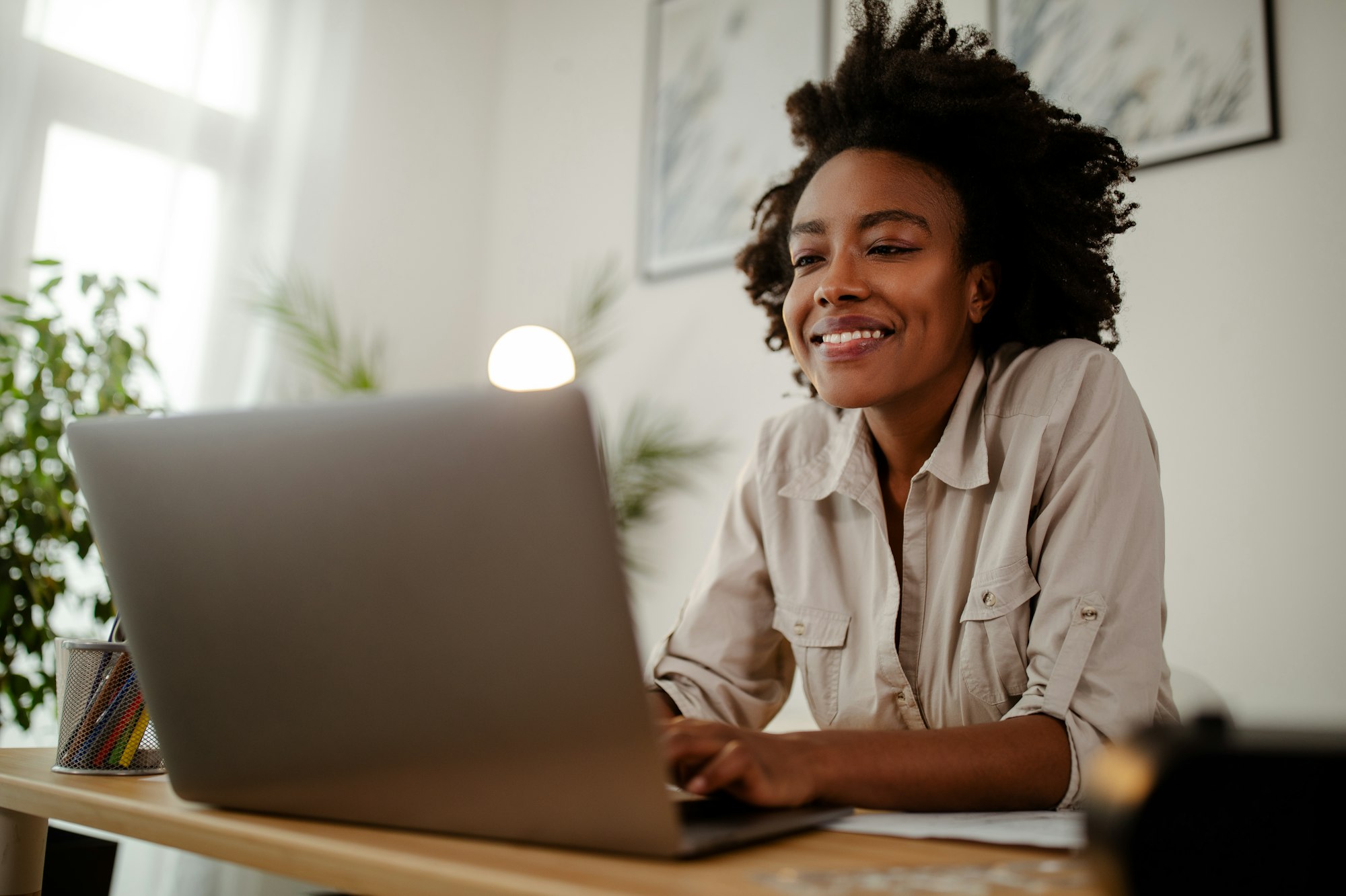 Young black smiling woman working at computer in an office.